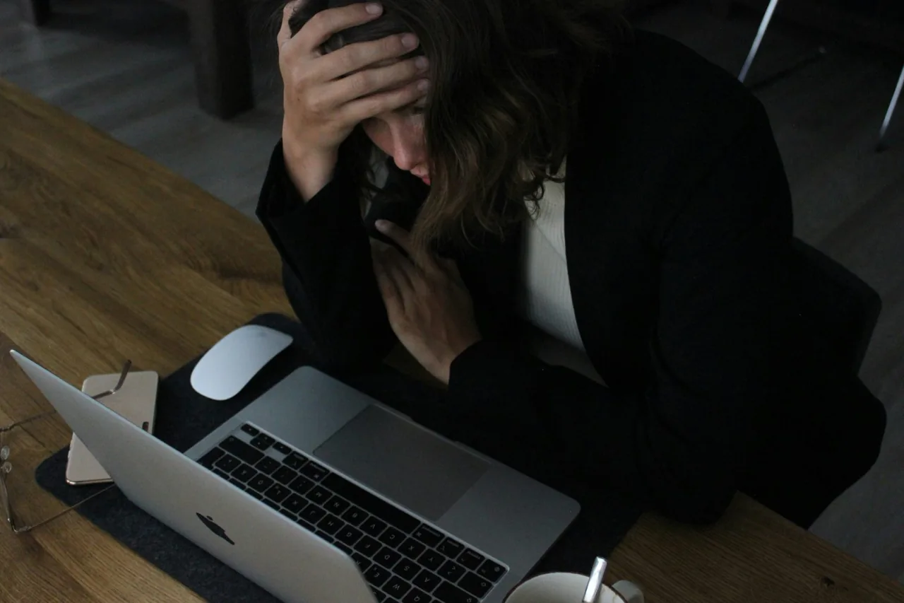 A professional feeling overwhelmed at her desk